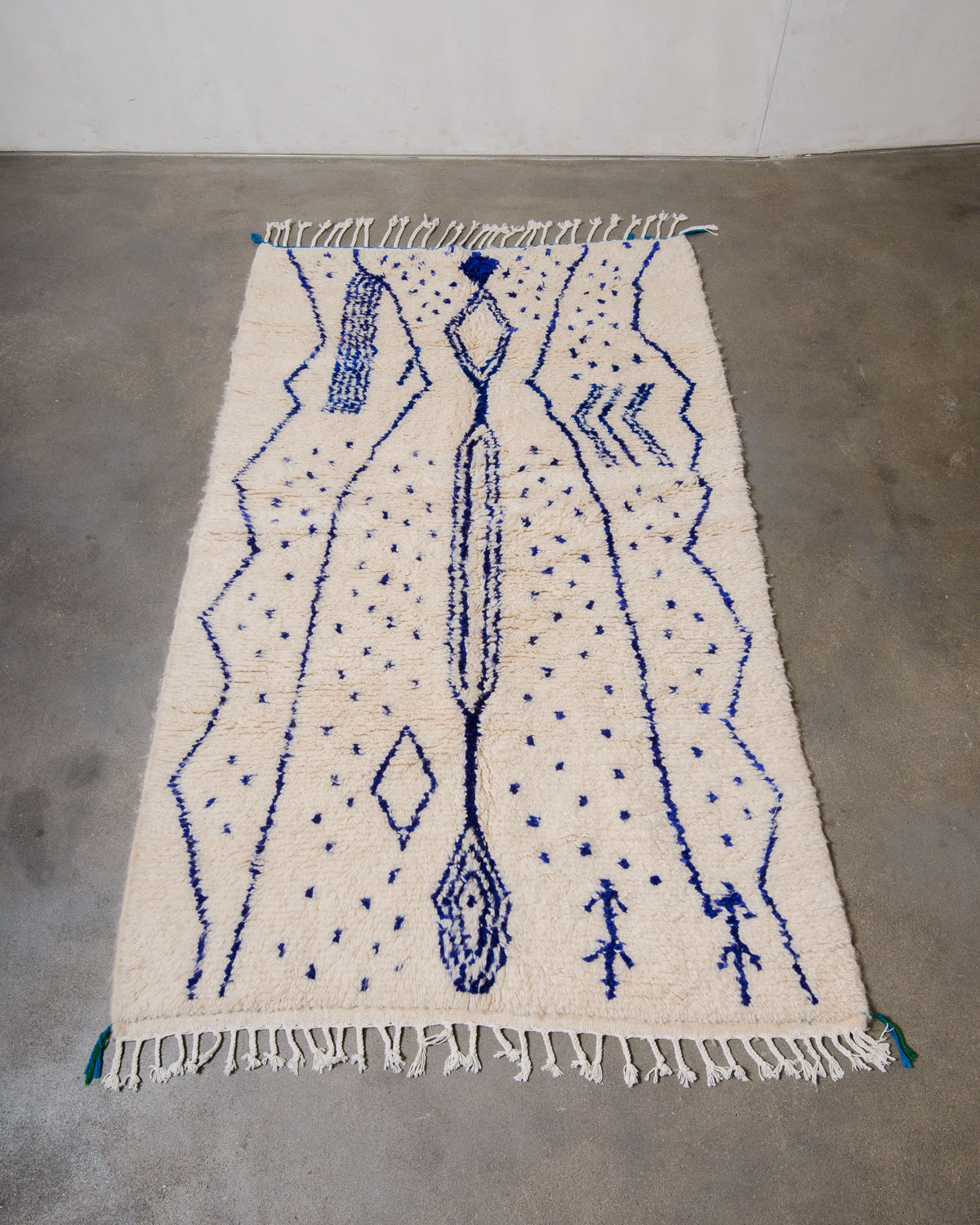 Berberlin Azilal rug made of fluffy wool and blue cotton, laying flat on a concrete floor.